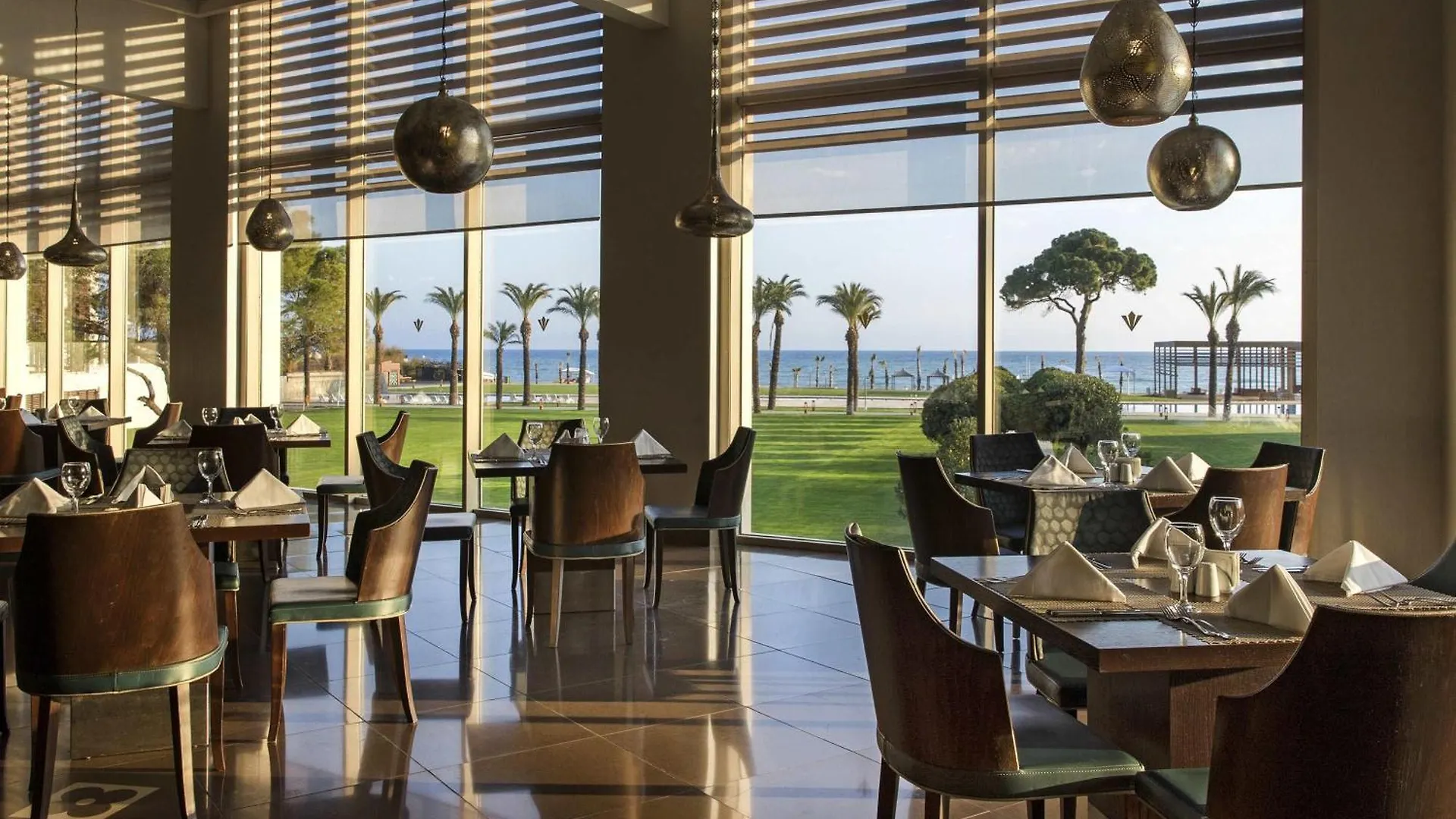 Rixos Premium Belek - The Land Of Legends Access Hotel Exterior photo This is a photo of a modern, elegant restaurant or dining area with large windows offering a beautiful view.

**Interior Details:**
*   The space has a sophisticated, contemporary design.
*   The floor is made of polished, dark-colored tile, which re